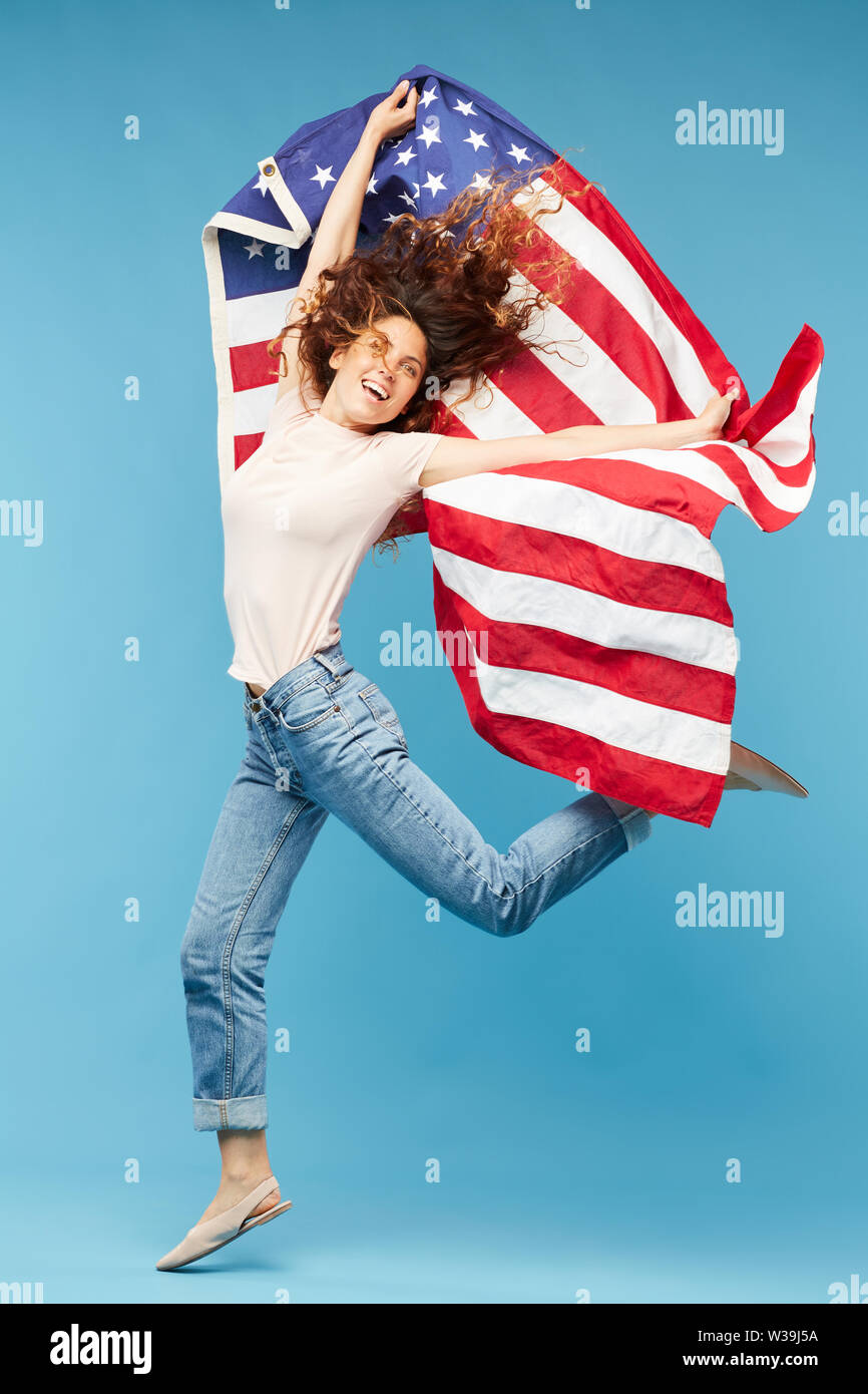 Jeune femme dynamique danser dans l'isolement avec les drapeau américain en mains Banque D'Images