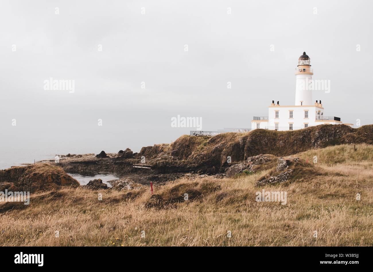 Phare blanc au sommet d'une colline donnant sur la côte écossaise. Paysage herbeux Banque D'Images