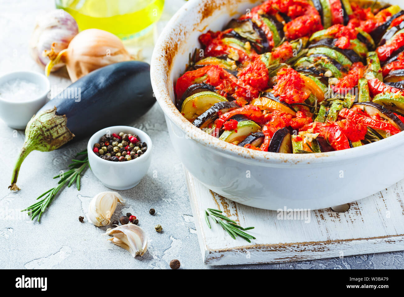 Ratatouille végétarien de aubergines, courgettes, tomates et sauce tomate et poivrons aux herbes en forme de céramique avant la cuisson. Style rustique. Banque D'Images