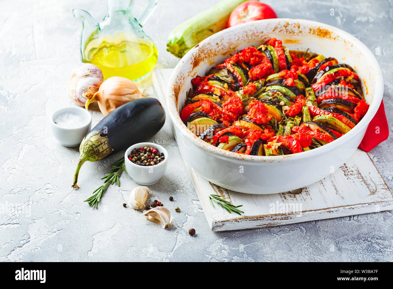 Ratatouille végétarien de aubergines, courgettes, tomates et sauce tomate et poivrons aux herbes en forme de céramique avant la cuisson. Style rustique. Banque D'Images