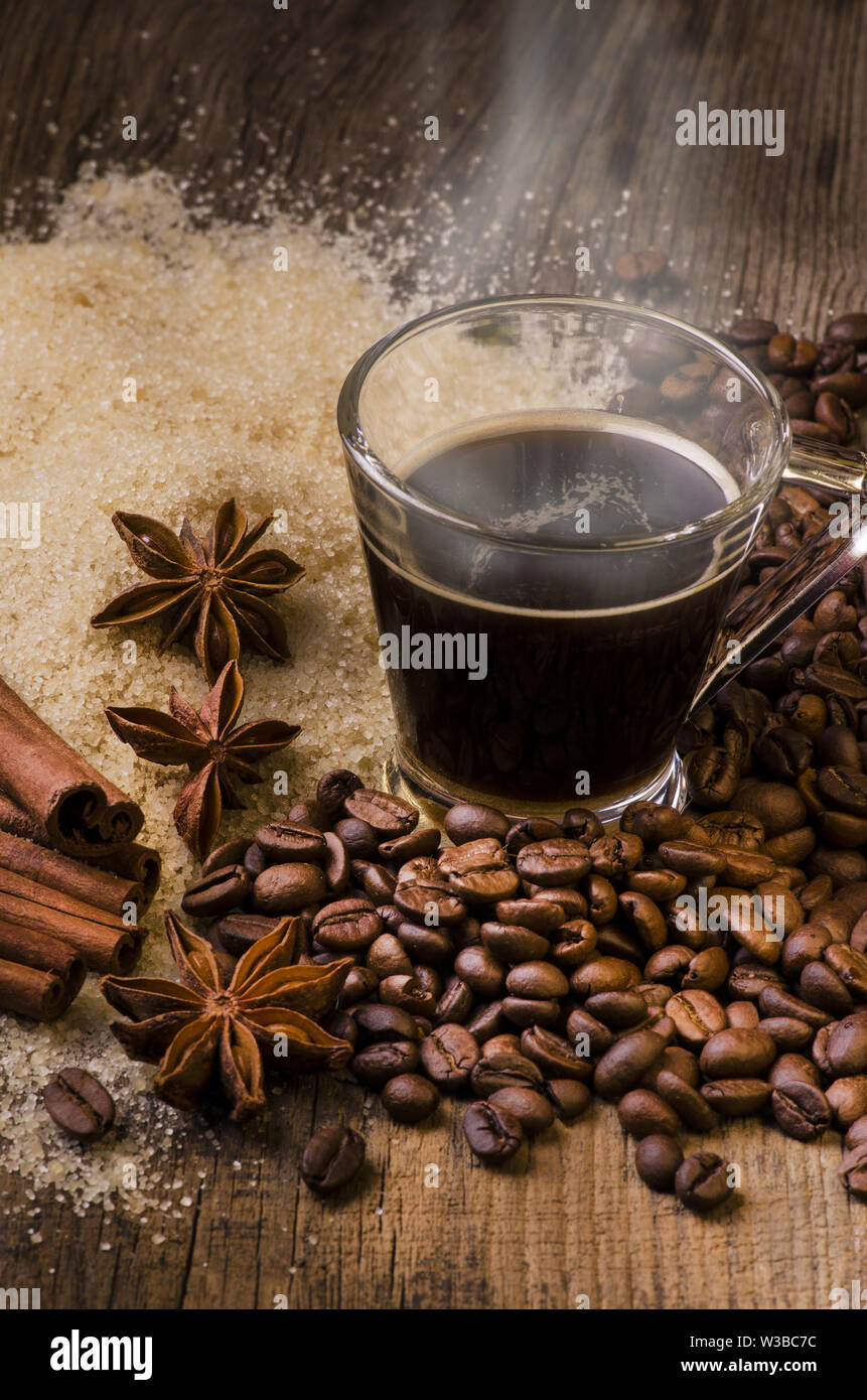 Café noir bouillant en petite tasse, les arômes, le sucre brun et le café  en grains grillé sur un fond de bois Photo Stock - Alamy