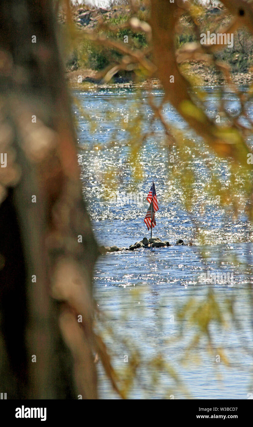 Drapeaux américains posté dans les roches au milieu de la vue sur la rivière entre les branches d'arbres Banque D'Images