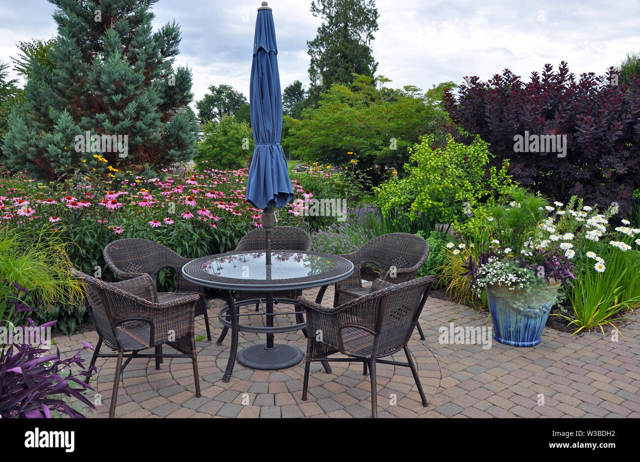Joli jardin patio avec table et chaises en osier Banque D'Images