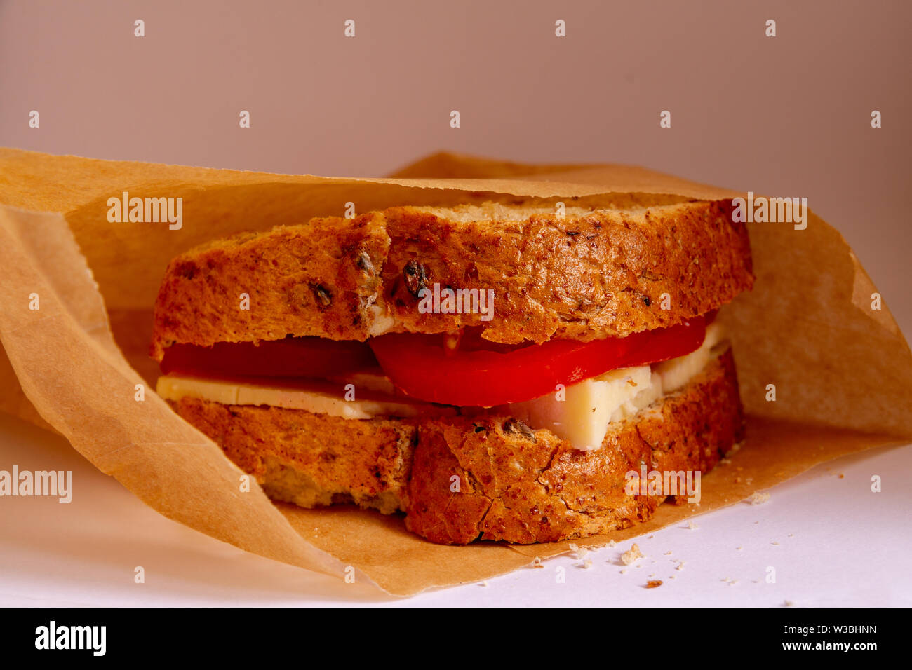 À la recherche dans un sac en papier brun à la tomate et fromage sandwich sur pain grenier Banque D'Images