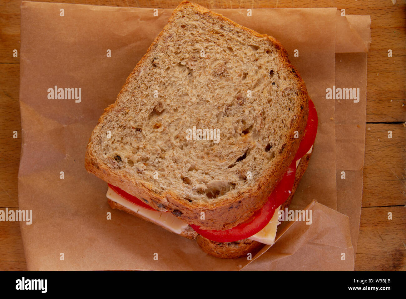 Regardant vers le bas sur une tomate et fromage sandwich sur grenier sur un sac en papier brun sur le dessus d'une vieille carte de pain Banque D'Images
