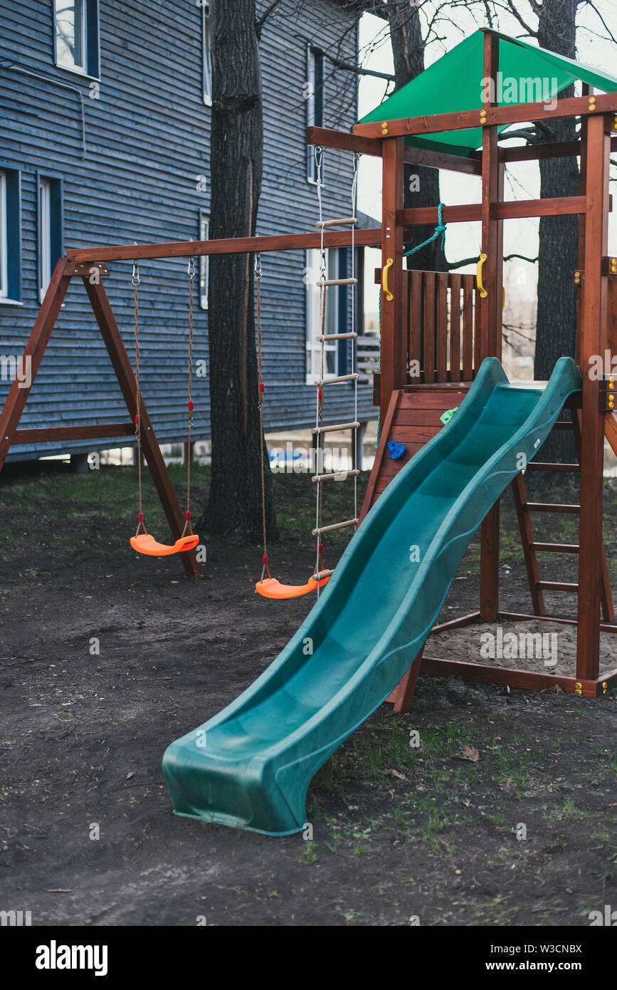 Faites glisser l'enfant plastique bleu sur un jeu en bois complexe. Aire de jeux pour enfants sans que personne. Banque D'Images