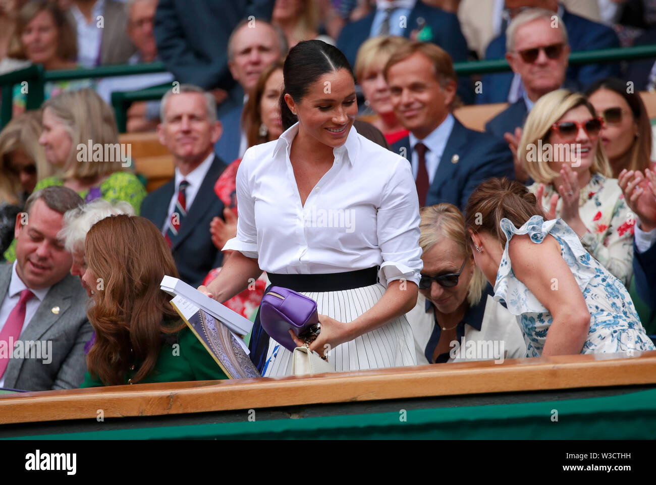 Wimbledon, Londres, Royaume-Uni. 13 juillet 2019. Meghan Markle (Duchesse  de Sussex) tient son non comprise sautoir violet avant de regarder la finale  dames entre Serena Williams et Simona au Wimbledon : tennis,