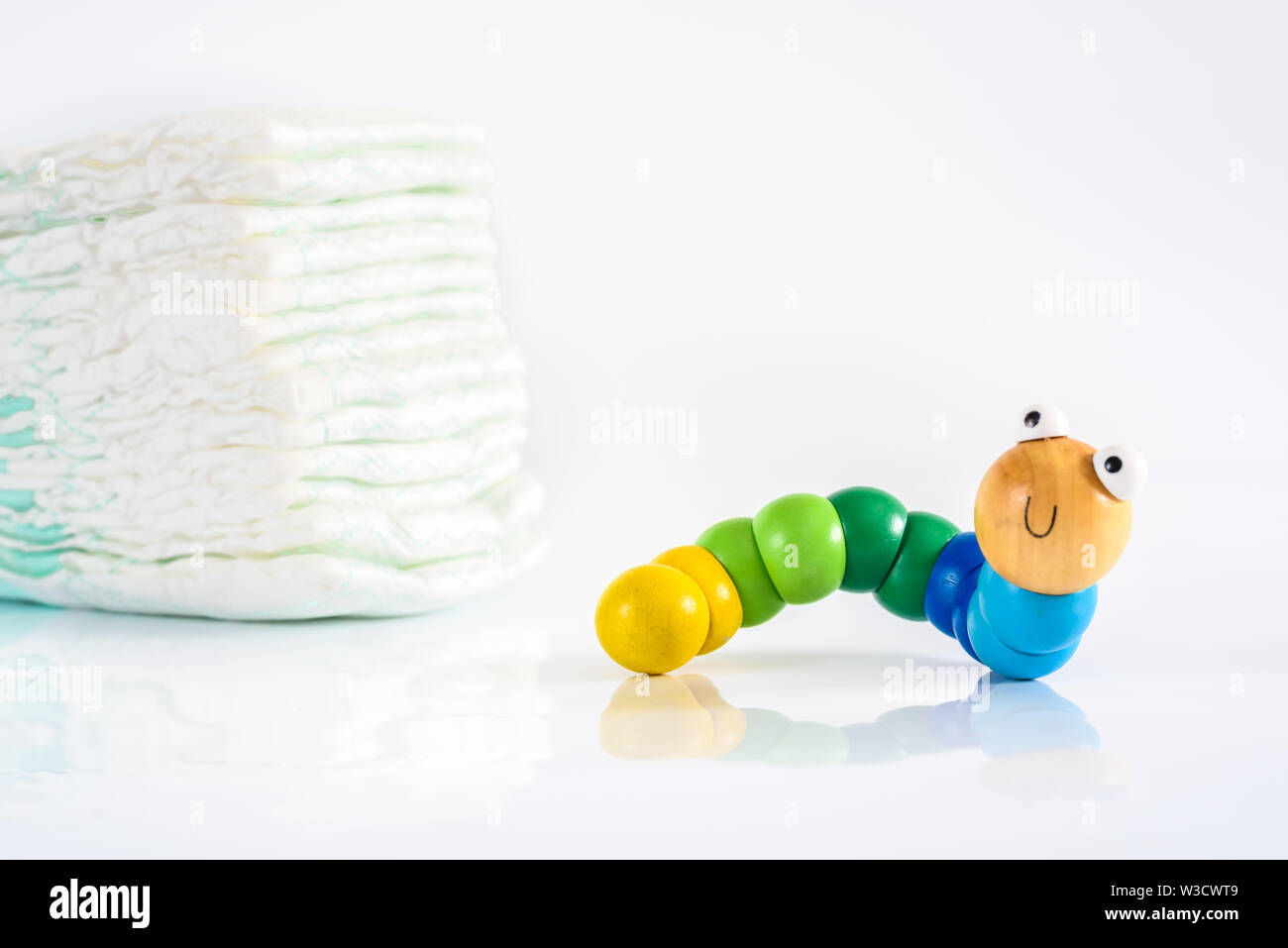 Toy ver avec sourire à côté d'une pile de couches, pour illustrer les concepts de la santé et de l'enfance maladies intestinales. Isolated on white Banque D'Images