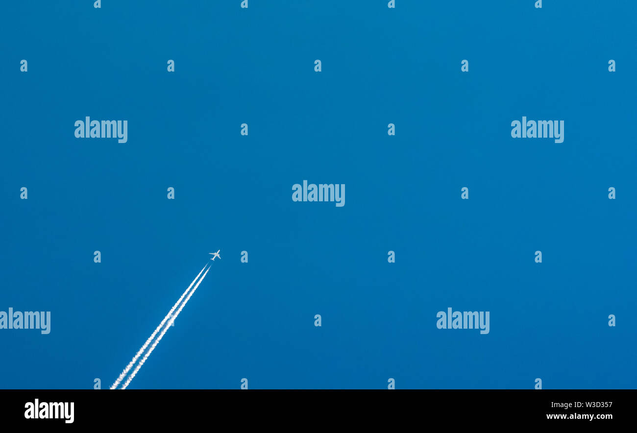 Avion avec condensation blanc pistes. Jet sur ciel bleu clair avec traînée de vapeur. Voyage par avion concept. Des sentiers à partir de gaz d'avion Banque D'Images