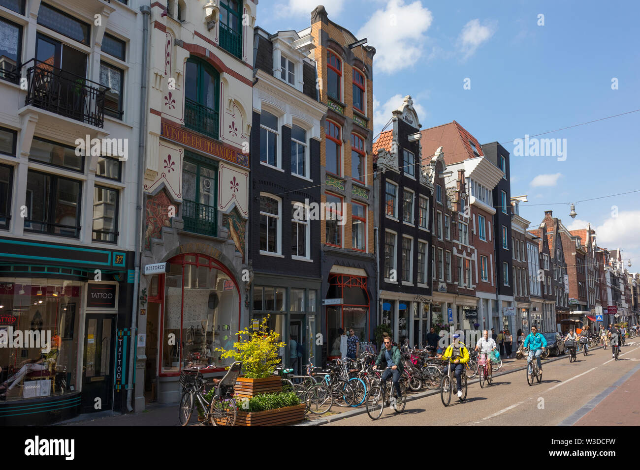 Amsterdam, Pays-Bas - 22 juin 2019 : Les cyclistes dans la Haarlemmerdijk avec ses maisons historiques à l'arrière-plan Banque D'Images