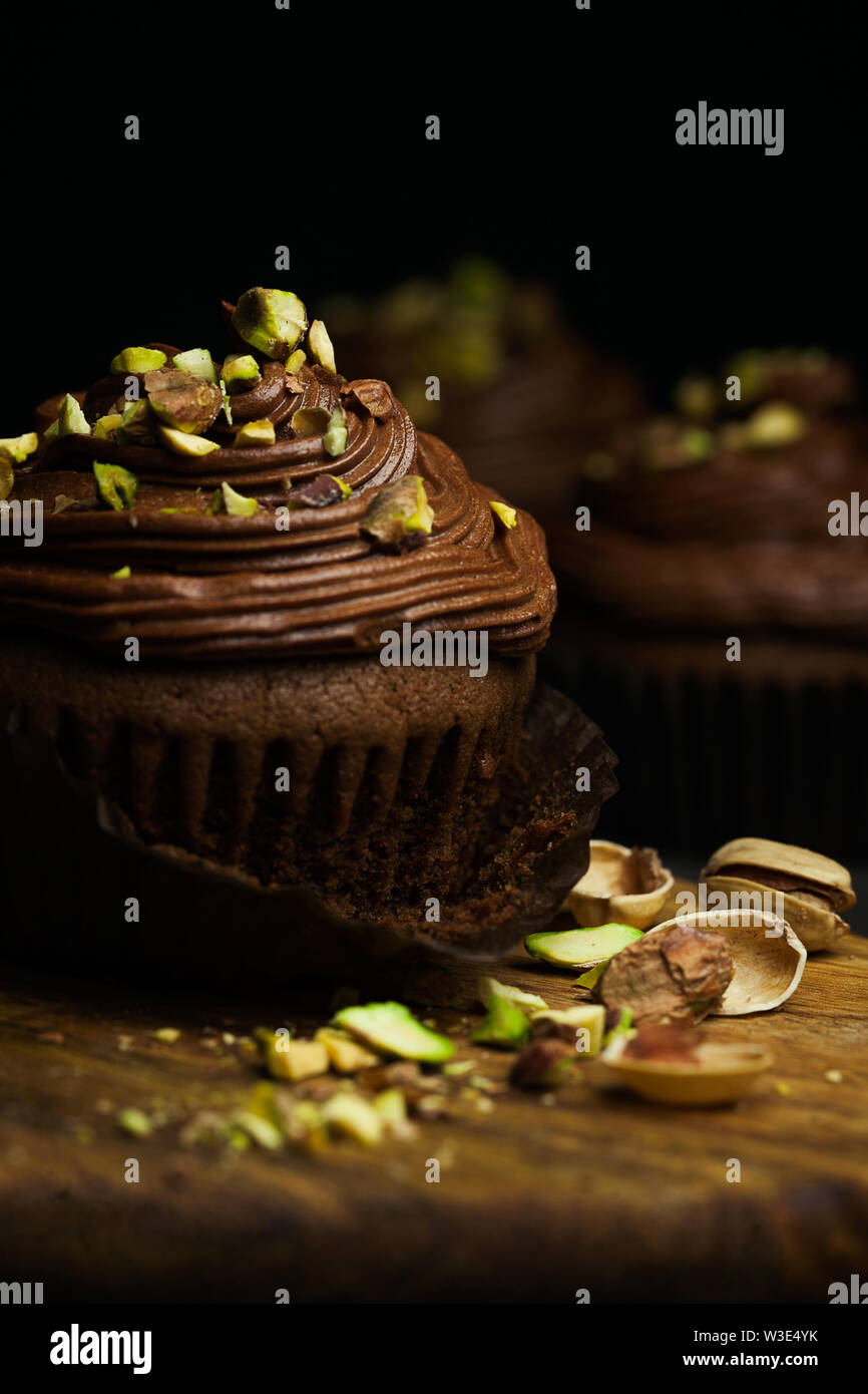 De beaux petits gâteaux au chocolat garnie de crème au beurre au chocolat pistache décoré sur fond sombre close-up.dessert maison.The food Banque D'Images