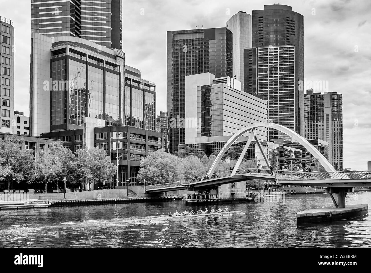 Belle vue en noir et blanc de la rivière Yarra, alors qu'une équipe d'athlètes l'aviron dans le centre de Melbourne, Australie Banque D'Images