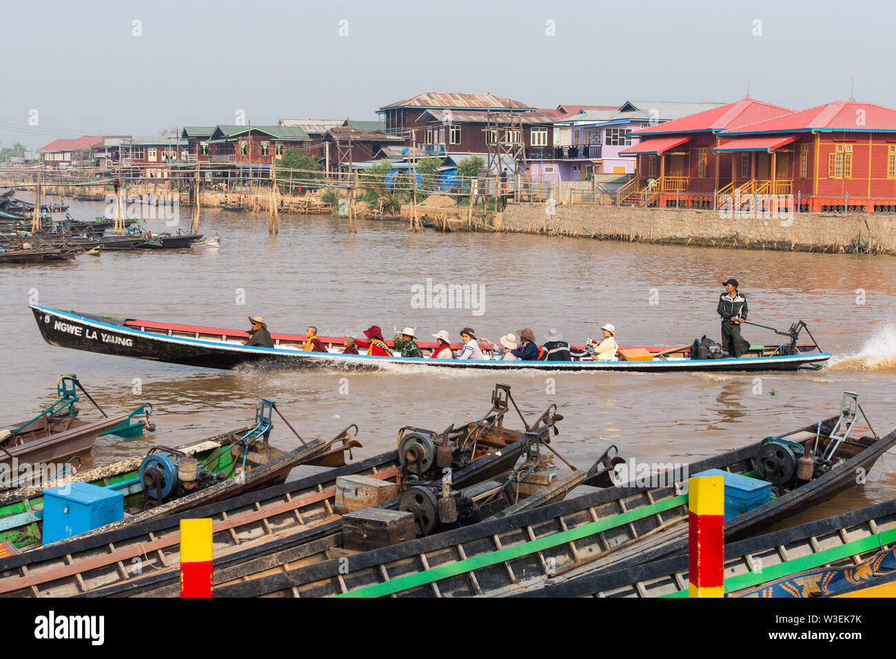 Haspres Thauk, Myanmar - Avril 2019 : Birman traditionnel maison flottante reflétant dans l'eau du lac Inle. Bateaux sur l'avant-plan. Banque D'Images