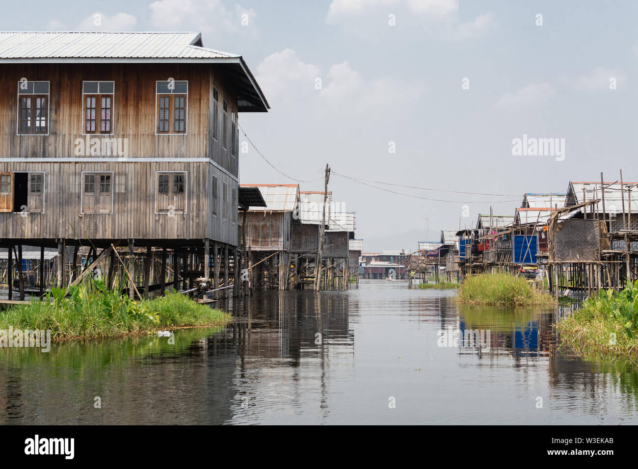 Haspres Thauk, Myanmar - Avril 2019 : Birman traditionnel maison flottante reflétant dans l'eau du lac Inle. Banque D'Images