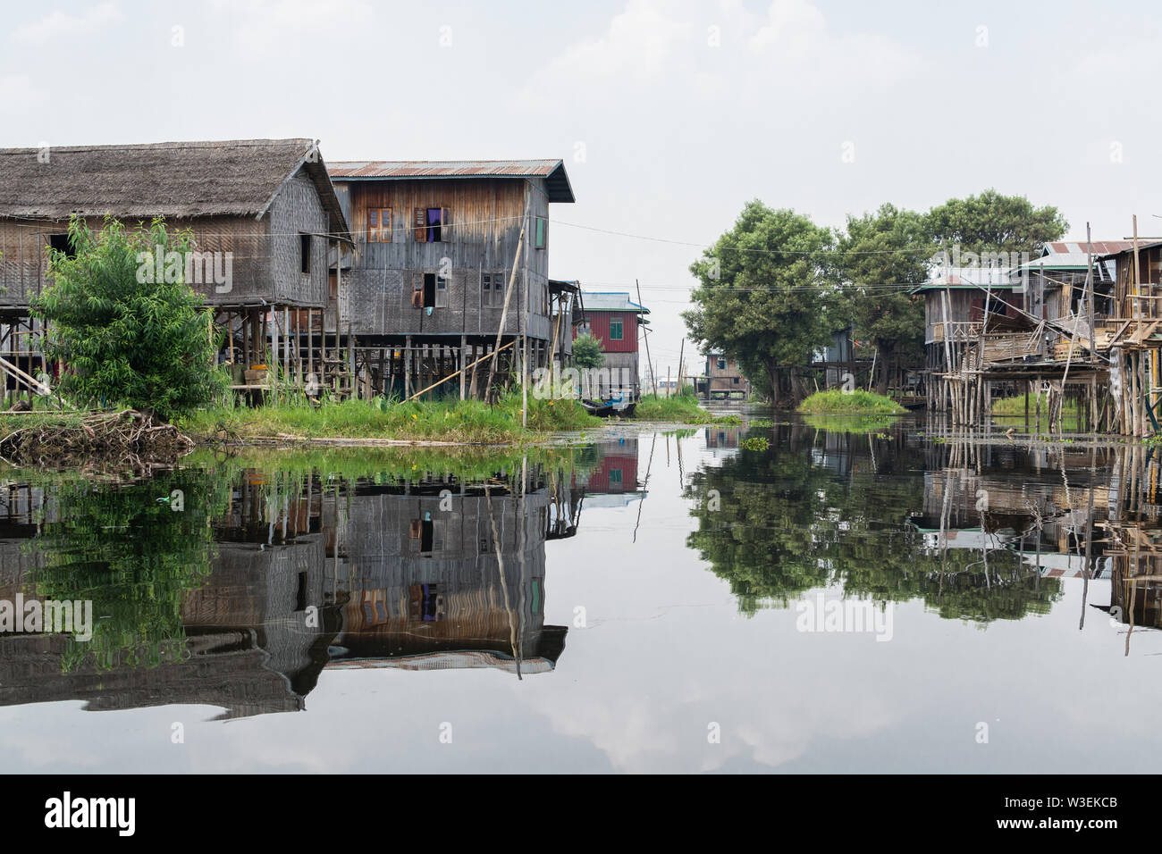 Haspres Thauk, Myanmar - Avril 2019 : Birman traditionnel maison flottante reflétant dans l'eau du lac Inle. Banque D'Images
