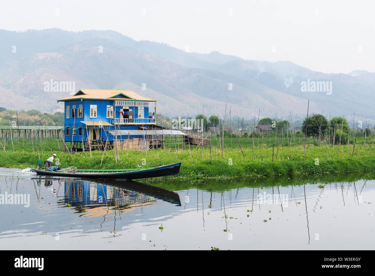 Haspres Thauk, Myanmar - Avril 2019 : Birman traditionnel maison flottante reflétant dans l'eau du lac Inle. Banque D'Images