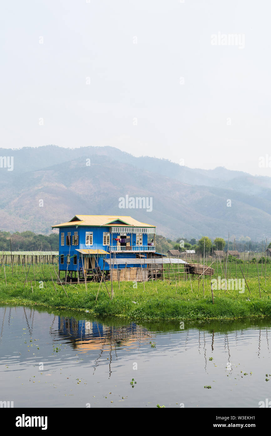 Haspres Thauk, Myanmar - Avril 2019 : Birman traditionnel maison flottante reflétant dans l'eau du lac Inle. Banque D'Images