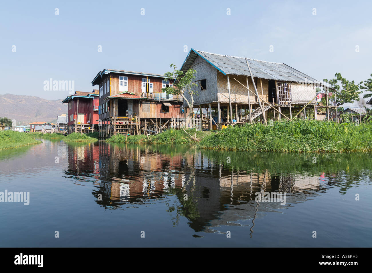 Haspres Thauk, Myanmar - Avril 2019 : Birman traditionnel maison flottante reflétant dans l'eau du lac Inle. Banque D'Images