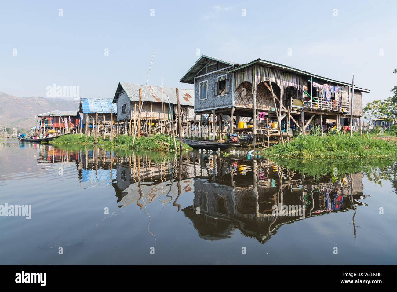 Haspres Thauk, Myanmar - Avril 2019 : Birman traditionnel maison flottante reflétant dans l'eau du lac Inle. Banque D'Images
