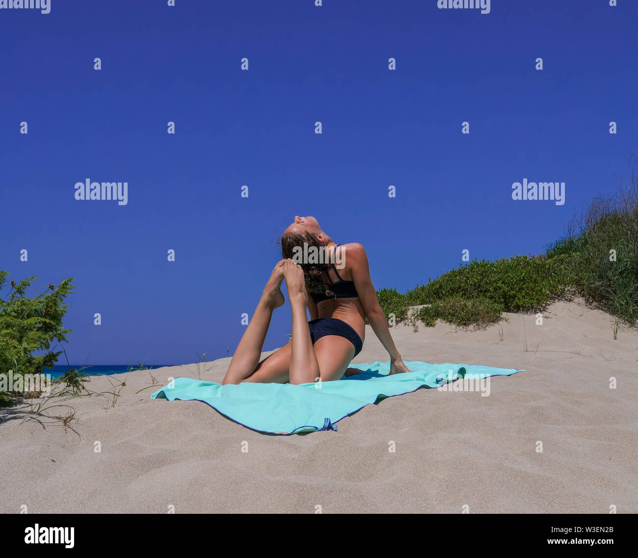 Et Slim athletic girl dans un bikini noir pratiquer yoga pose back bend avant un magnifique ciel bleu sur une plage de sable. Convient pour Fitness, Bien-être, Banque D'Images