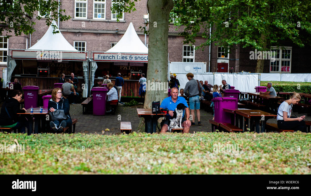 Un homme est assis avec son chien au point d'alignement avant l'événement de marche.La Marche internationale de quatre jours, appelé 'Vierdaagse' à Nijmegen est devenue le plus grand événement de marche de plusieurs jours dans le monde entier. La veille, tous les marcheurs rendez-vous pour aller chercher leur collet avec le nombre d'inscription au début de la promenade. Banque D'Images