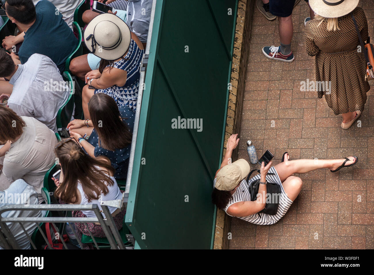 Birds Eye View de spectateurs, porter un chapeau, et à l'aide de téléphone mobile, au championnat de tennis de Wimbledon Banque D'Images