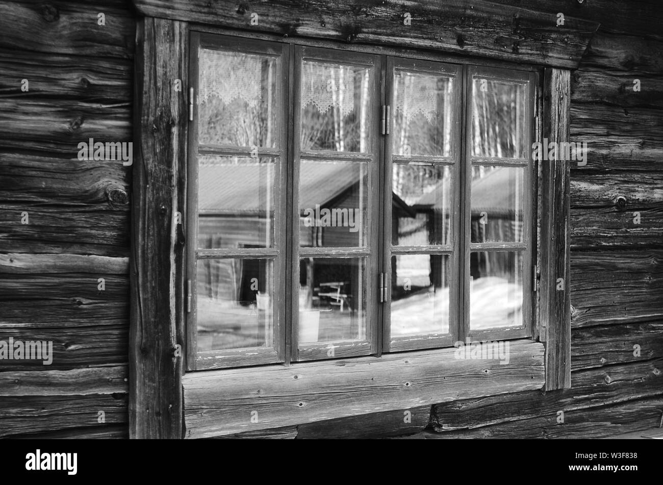 Miroir noir et blanc vue de l'extérieur d'une fenêtre d'une vieille maison en bois en Dalécarlie rural,Suède. Banque D'Images