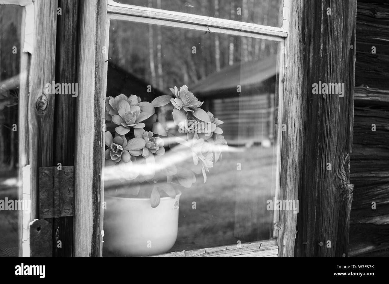 Miroir noir et blanc vue de l'extérieur d'une fenêtre d'une vieille maison en bois en Dalécarlie rural,Suède. Banque D'Images