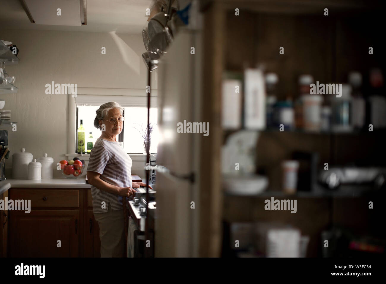 Hauts femme debout dans sa cuisine avec un air sérieux. Banque D'Images