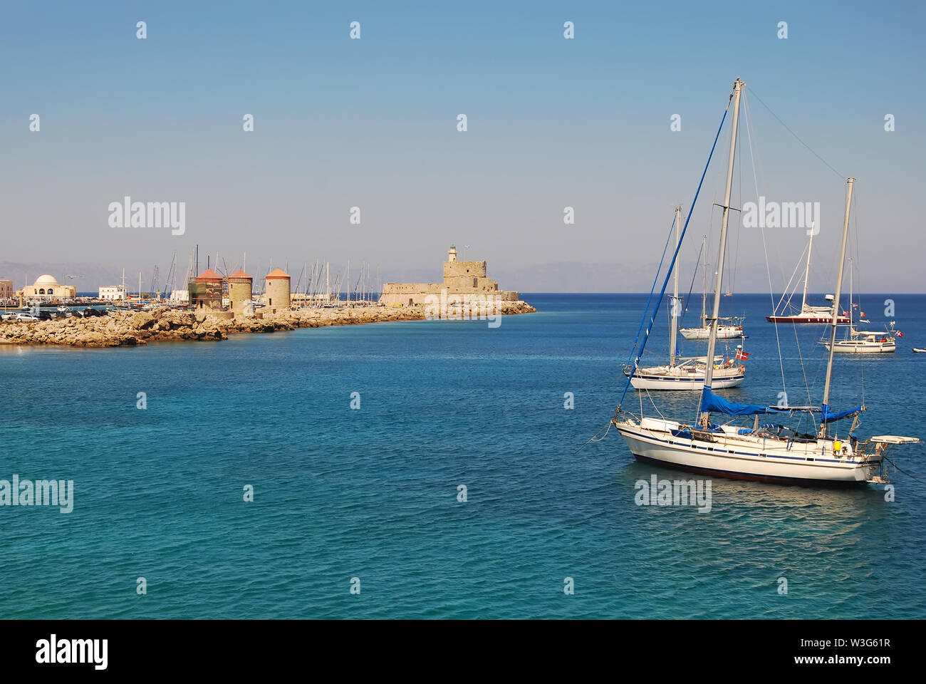 Rhodes : Fort de Saint Nikolas, grec moulins à vent. Yachts dans le port de Mandraki Banque D'Images