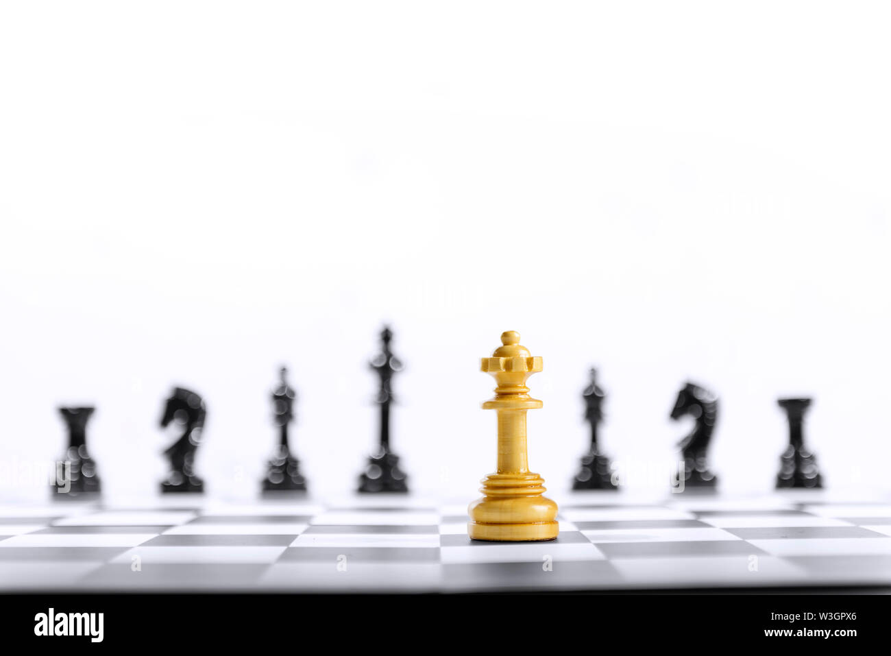 Pièce d'échecs reine en bois debout devant tout le groupe de pièces d'échecs noir sur l'échiquier Banque D'Images