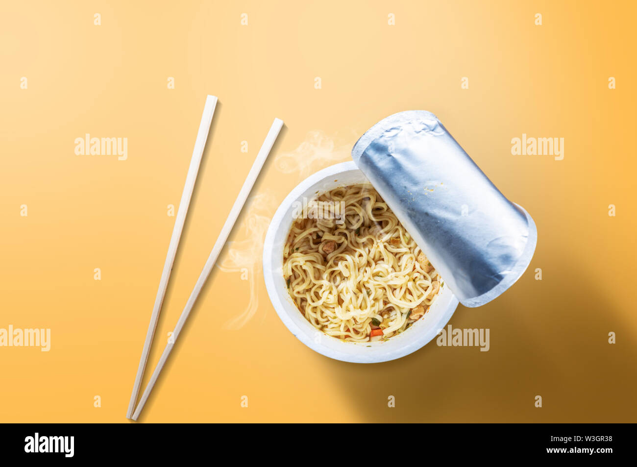 Instant cup noodle avec chopstick sur fond jaune Banque D'Images