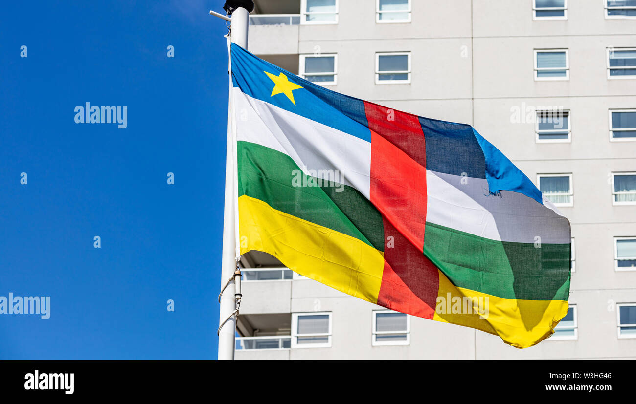 Drapeau de la République d'Afrique centrale. Symbole national en agitant sur perche haut bâtiment, et fond de ciel bleu clair, journée ensoleillée. Indepedence day concept. Banque D'Images