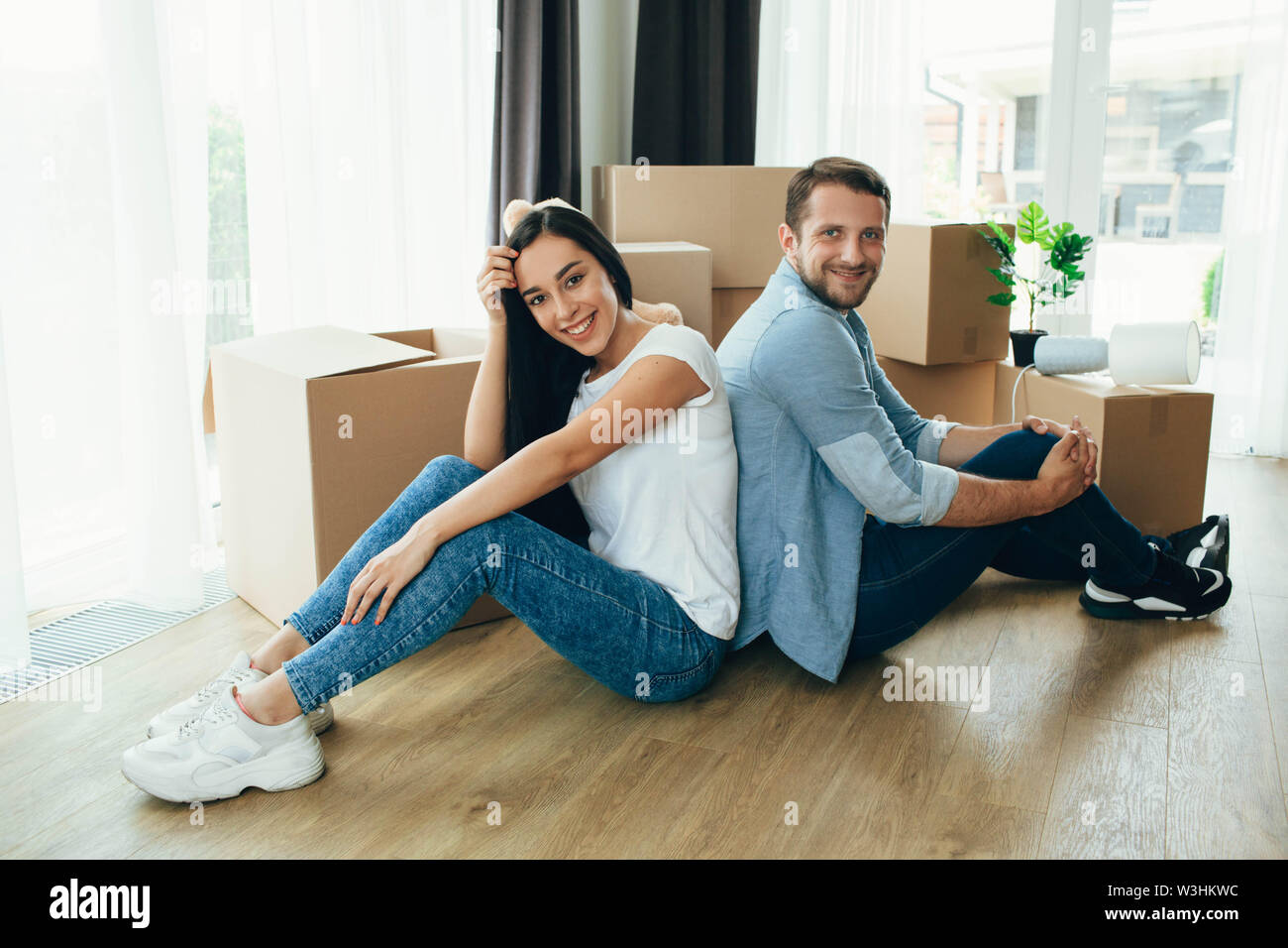 Jeune couple assis près de boîtes de carton, déménagement nouvelle maison Banque D'Images