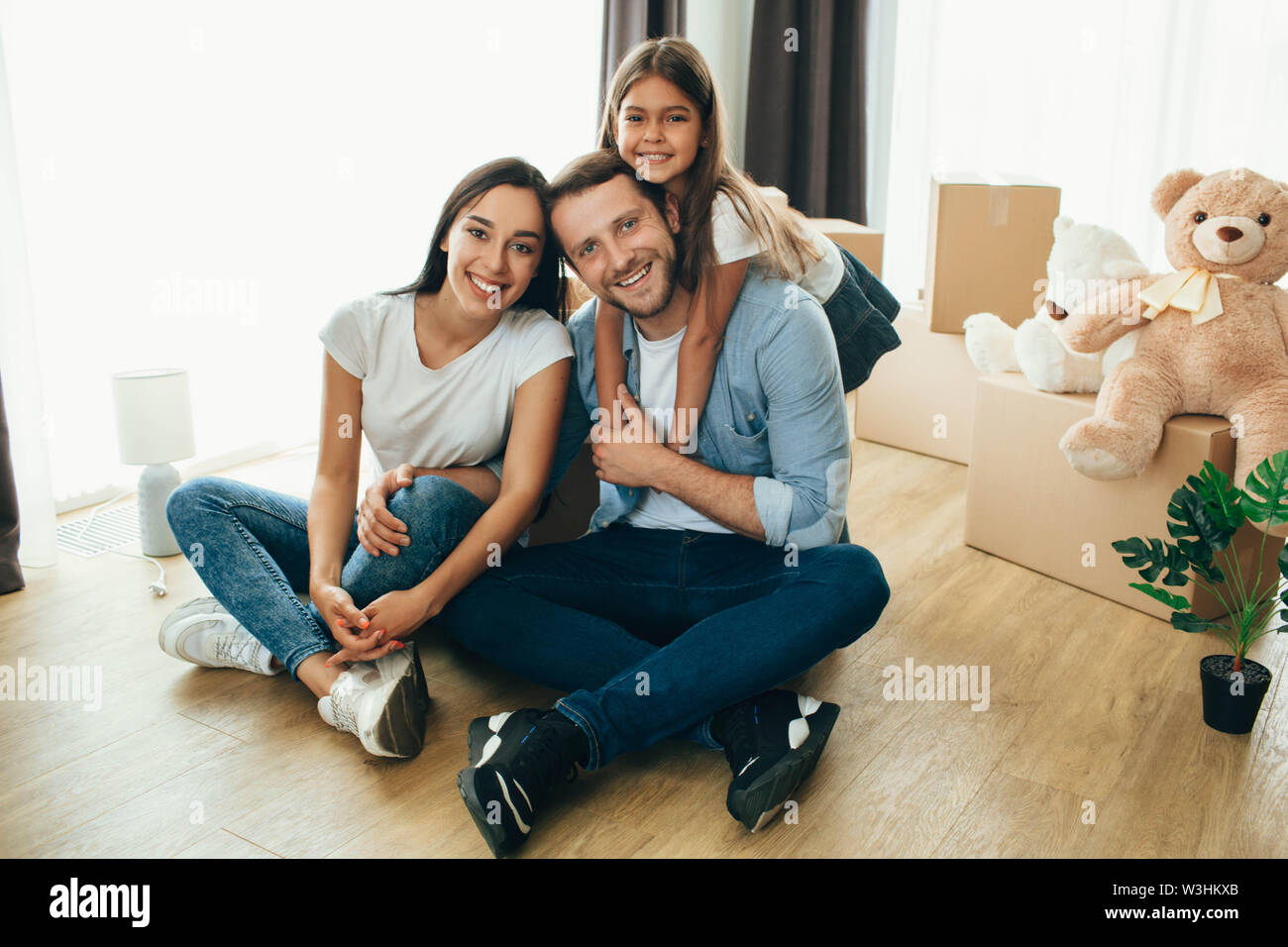 Heureux couple avec un enfant assis à étage dans maison neuve Banque D'Images