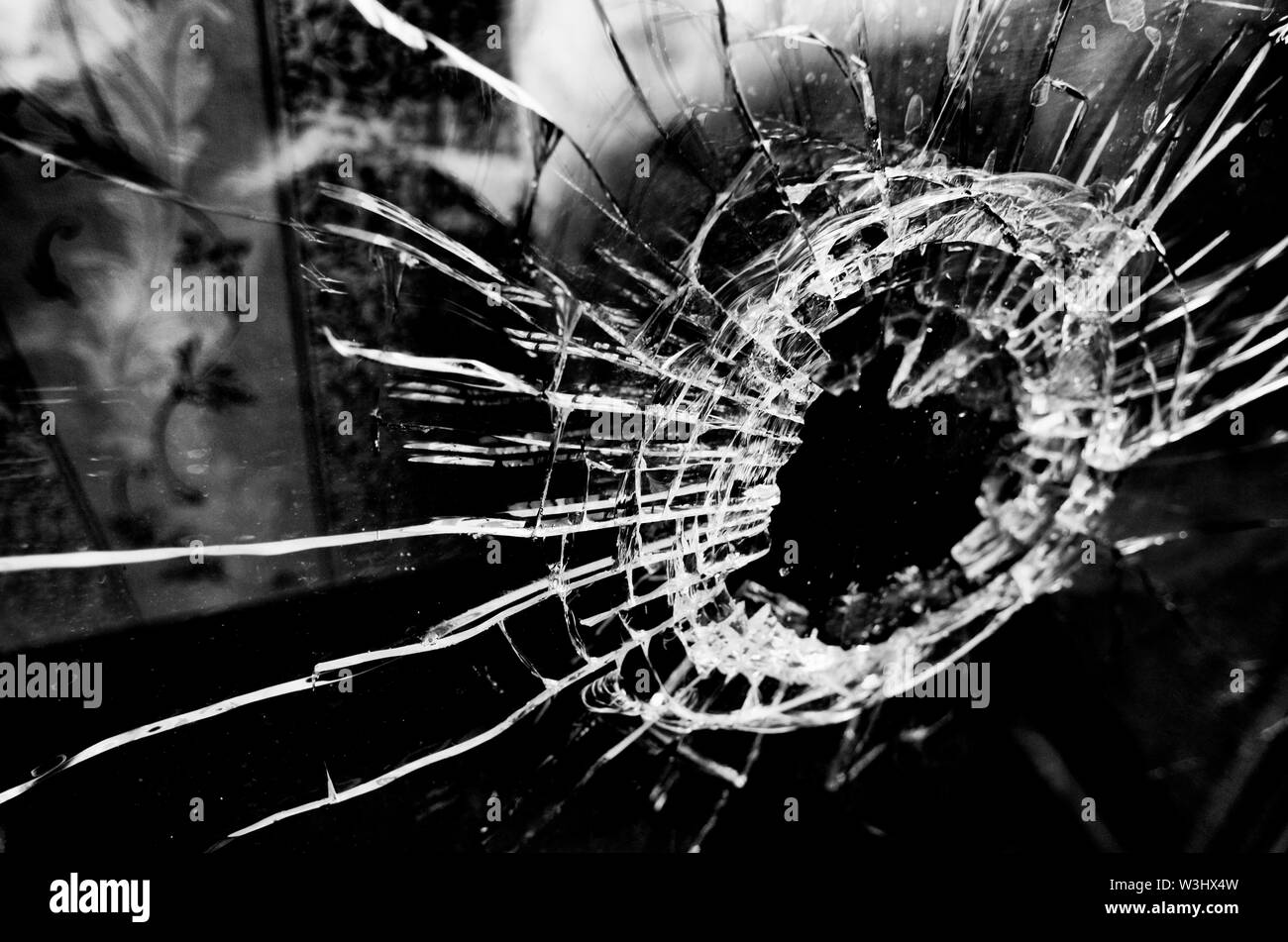 Beaucoup de fissures et un trou dans la fenêtre en verre noir et blanc stylisé et film lomography Banque D'Images