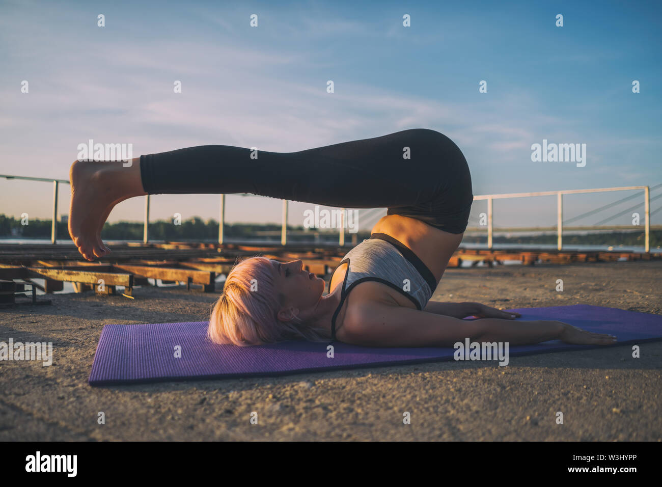 Woman practicing yoga on journée ensoleillée. Halasana / pose de charrue Banque D'Images