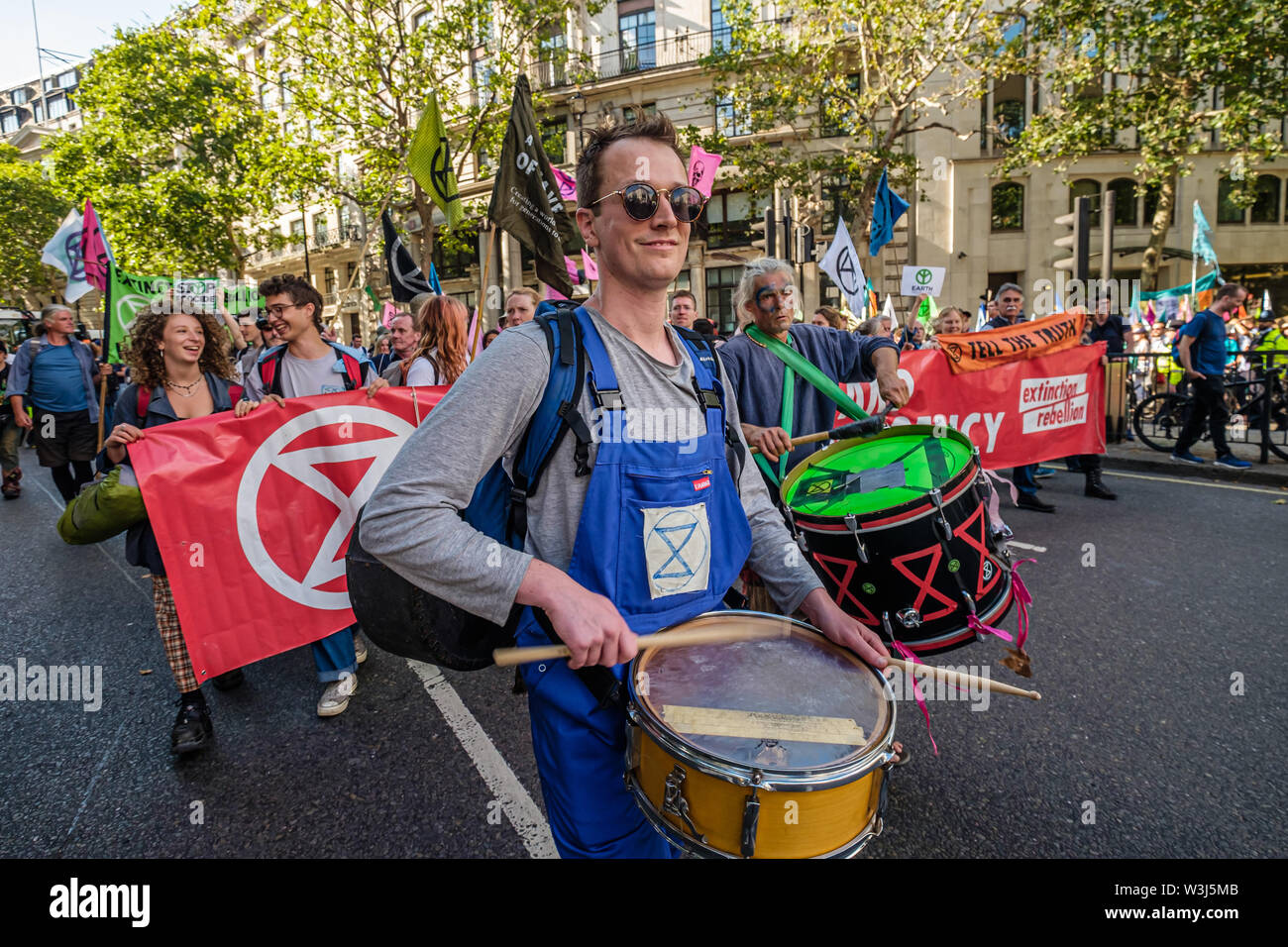 Londres, Royaume-Uni. 15 juillet 2019. Tambours à l'avant de la rébellion de l'extinction de la mars Royal Courts of Justice à leur site pour les trois jours à Waterloo millénaire vert. De même que les manifestants avec des bannières, il y avait une rose géante dodo, et à l'arrière de la procession le yacht Polly Higgins, nommé pour l'avocat qui se sont battus pendant des années pour une loi contre l'écocide et est décédé au mois d'avril. Crédit : Peter Marshall/Alamy Live News Banque D'Images