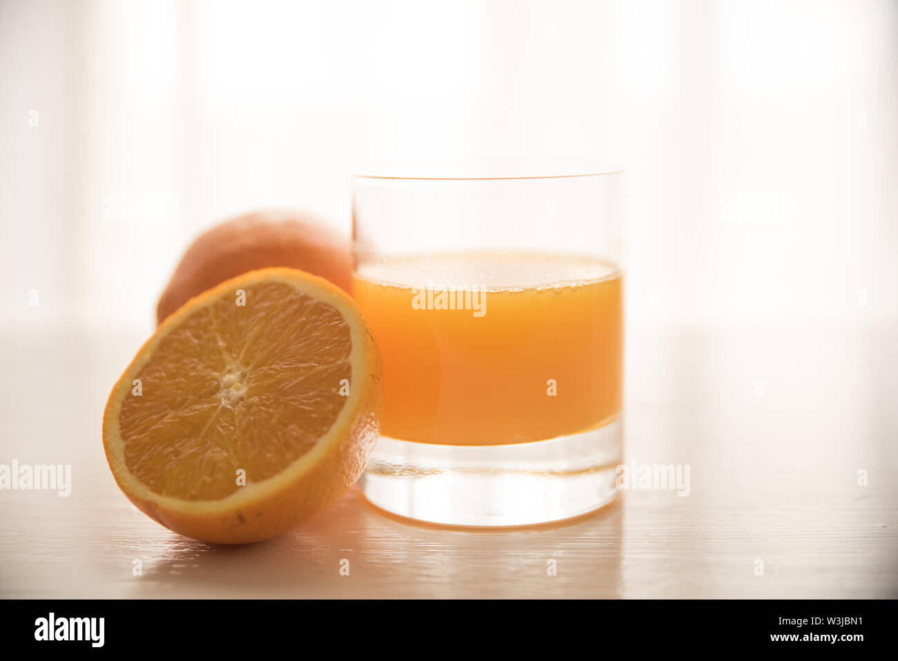 Les oranges avec un verre de jus d'orange sur un fond de table blanc Banque D'Images