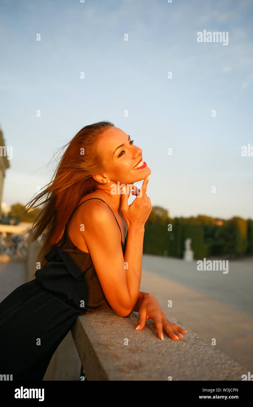Jeune femme romantique avec dents sourire rêvasser à propos avenir dans le coucher du soleil Banque D'Images
