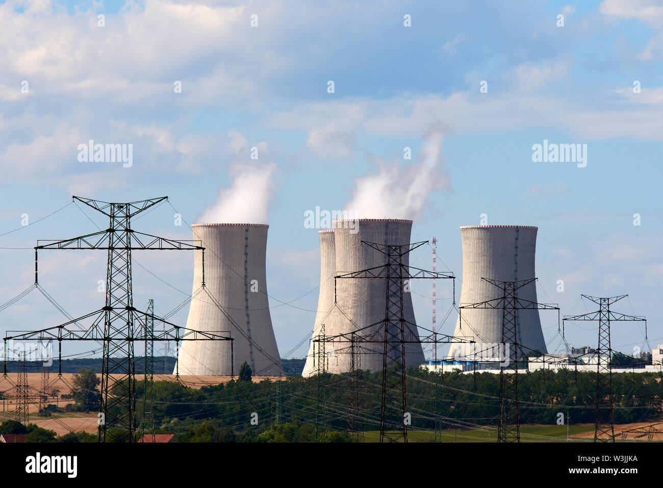 Avis de fumeurs cheminées de centrale nucléaire, les lignes d'alimentation et de la forêt, sous ciel bleu avec des nuages blancs Banque D'Images