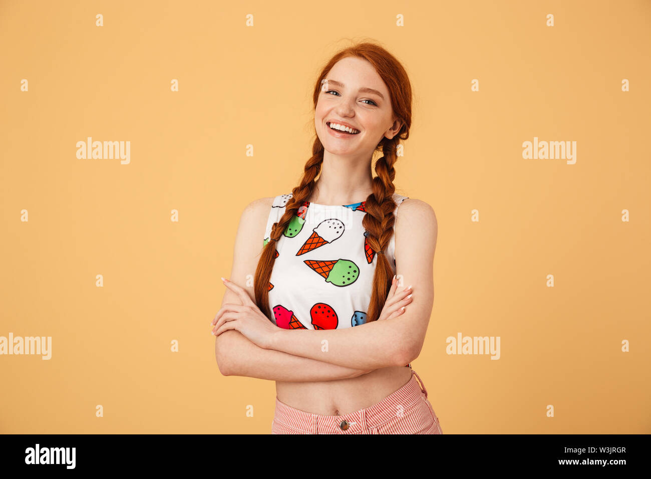 Image de belle Rousse femme vêtue de ice cream imprimé t-shirt posant sur fond jaune isolé. Banque D'Images