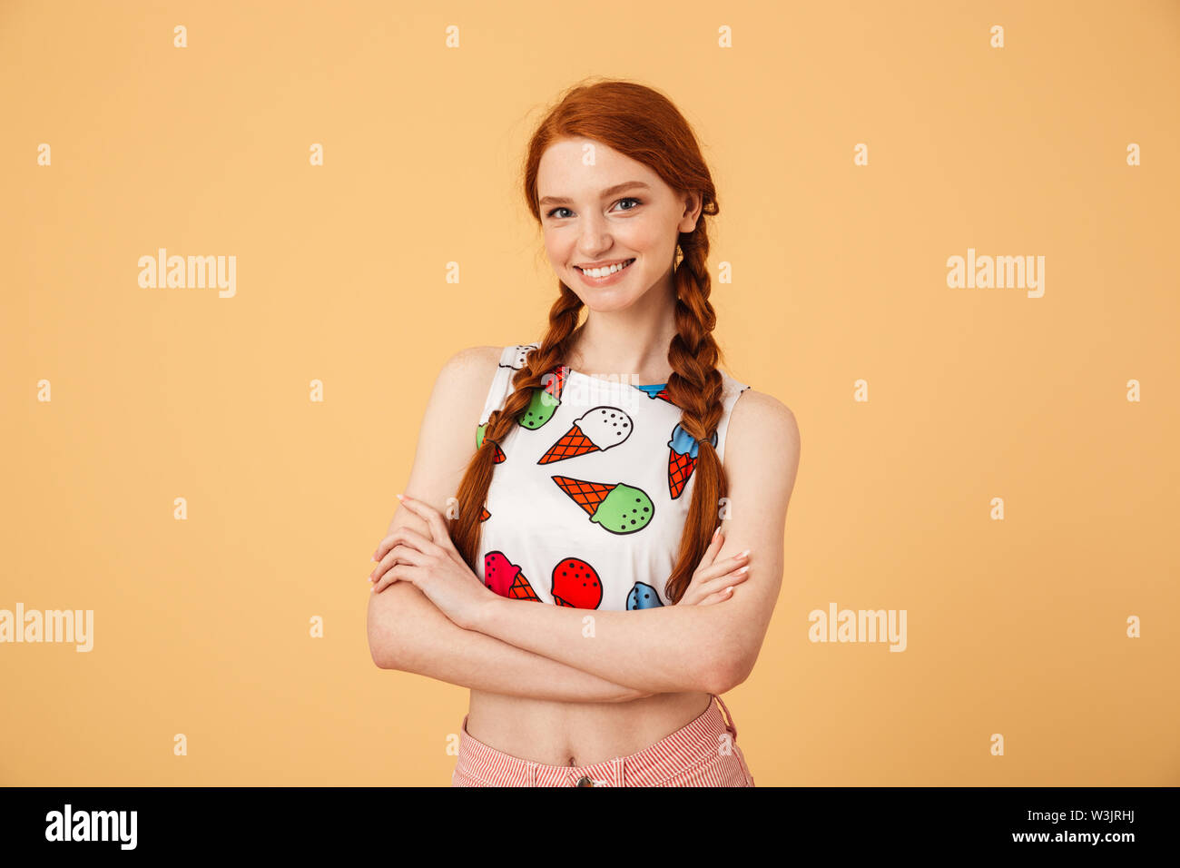 Photo de smiling belle Rousse femme vêtue de ice cream imprimé t-shirt posant sur fond jaune isolé. Banque D'Images