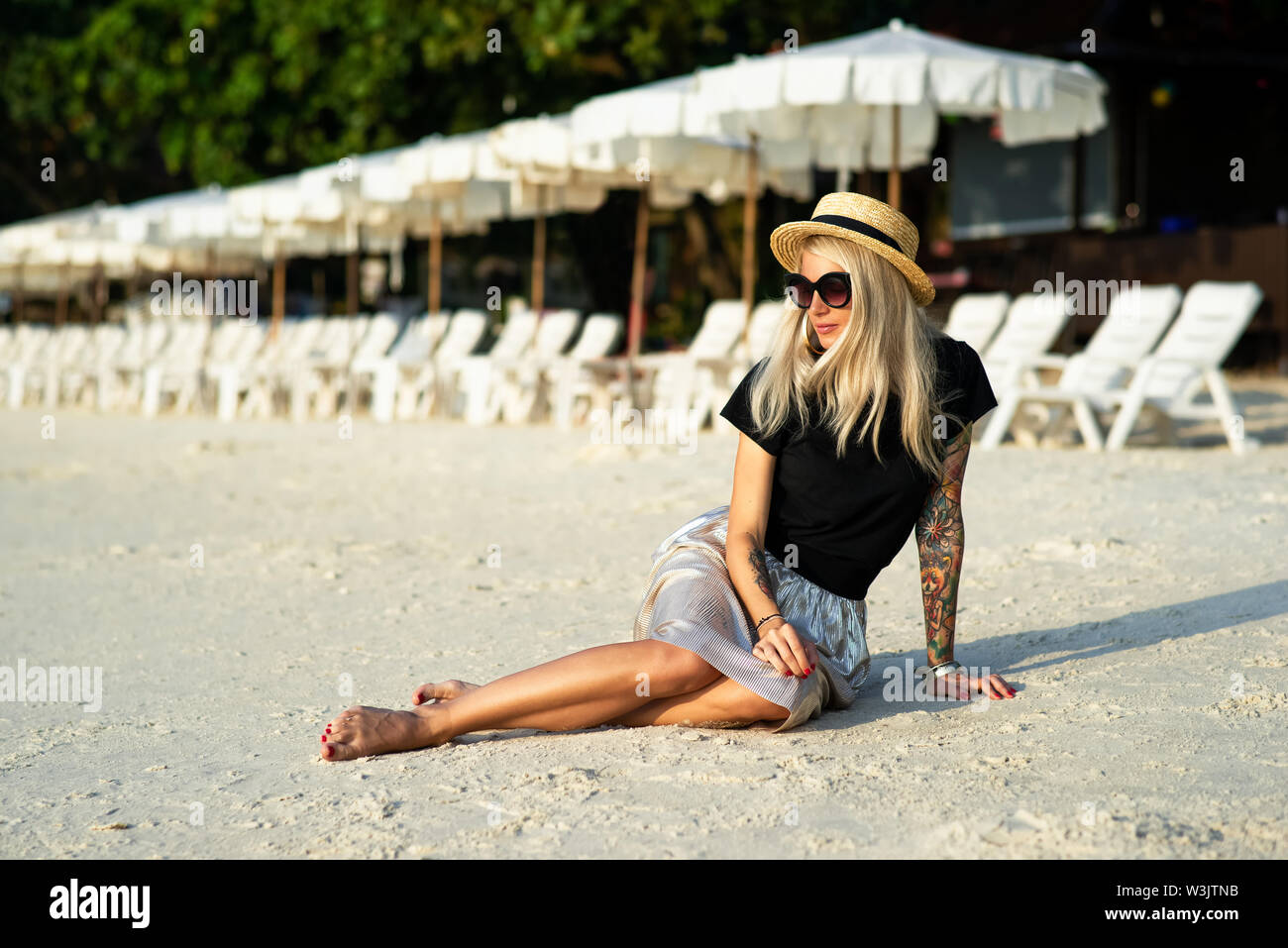 Une fille dans un chapeau de paille se trouve sur la plage le matin. Jeune fille moderne en vacances Banque D'Images