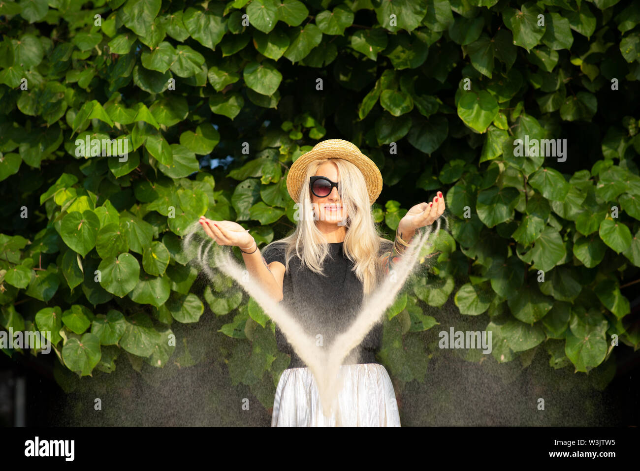 La plage de sable se réveille de la mains d'une belle blonde à lunettes de soleil. Vacances à la plage. Portrait d'une jeune fille moderne. Banque D'Images