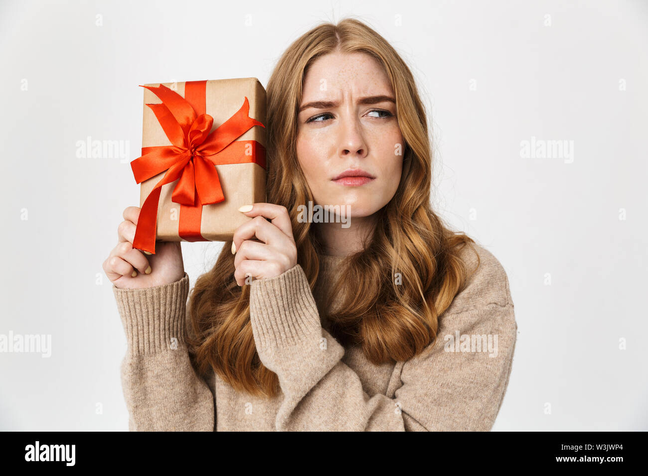 Belle jeune fille confus portant sweater isolés sur fond blanc, avec boîte-cadeau Banque D'Images