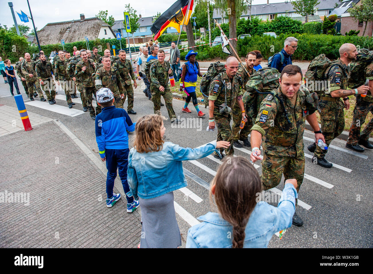 Les enfants donnent des bonbons aux soldats de l'Allemagne lors de l'événement.Les quatre jours de marche sont un événement réalisation pendant quatre jours consécutifs, où chaque année des dizaines de milliers de marcheurs participent. Ces jours, les gens du monde entier viennent à Nimègue pour marcher dans et autour de la ville et ses beaux environs boisés. Des milliers de spectateurs sont en train d'encourager les marcheurs le long de la route tous les jours. Après quatre jours de marche, une glorieuse entrée le long de la Via Gladiola attend les marcheurs, suivie de la distribution de leurs quatre jours bien méritée Médaille. Banque D'Images