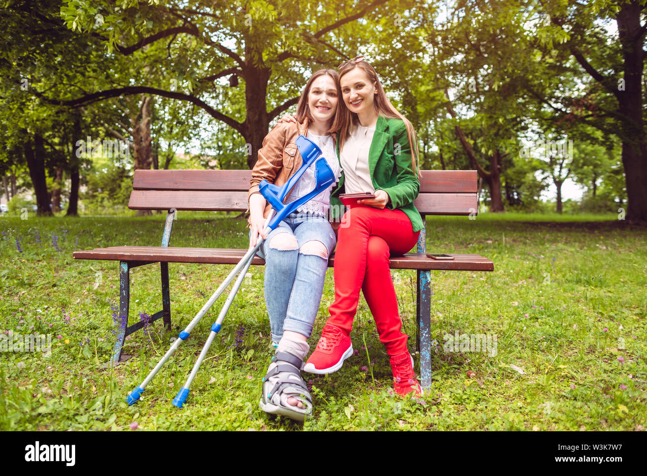 Deux femmes, un environnement sain et une avec une entorse du pied, sur un banc Banque D'Images