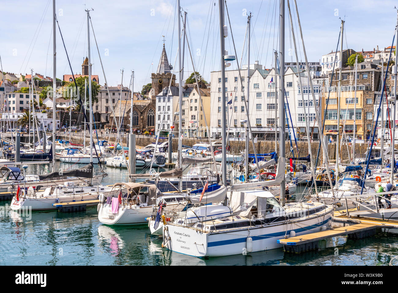 Dans le port des yachts amarrés en face de la ville, église St Peter Port, Guernsey, Channel Islands UK Banque D'Images