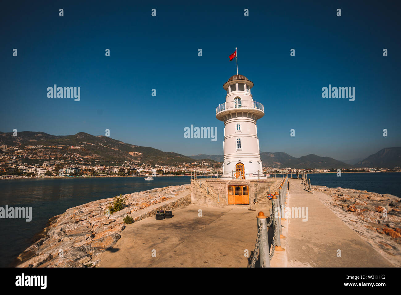 Nice et petit phare blanc à port d'Alanya avec de grands vieux bateau en arrière-plan, de la Turquie, Antalya district Banque D'Images